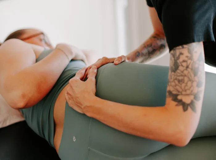 Two hands palpating the hip of a patient lying on their side