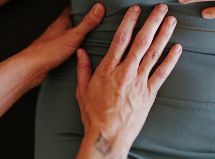 Two hands palpating a patient's hip along the waistband