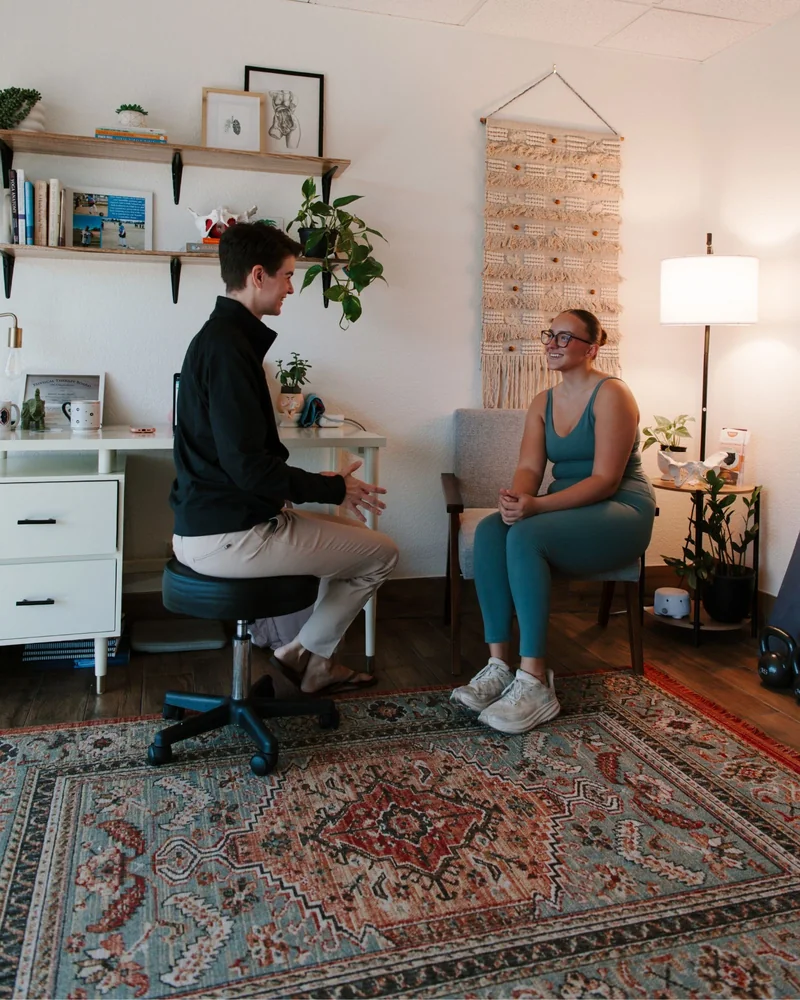 Dr. Hare on a stool in conversation with a patient in the armchair